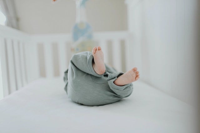 A 1 week old baby in a crib while parents are learning how to get a newborn to sleep from an infant sleep consultant