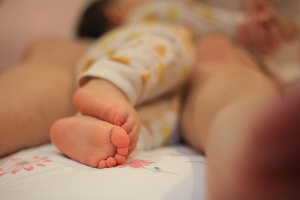 Baby feet, laying down to sleep with parent. No cry sleep methods can be an option for tired parents. The Peaceful Sleeper, sleep expert, is here to help you rest.