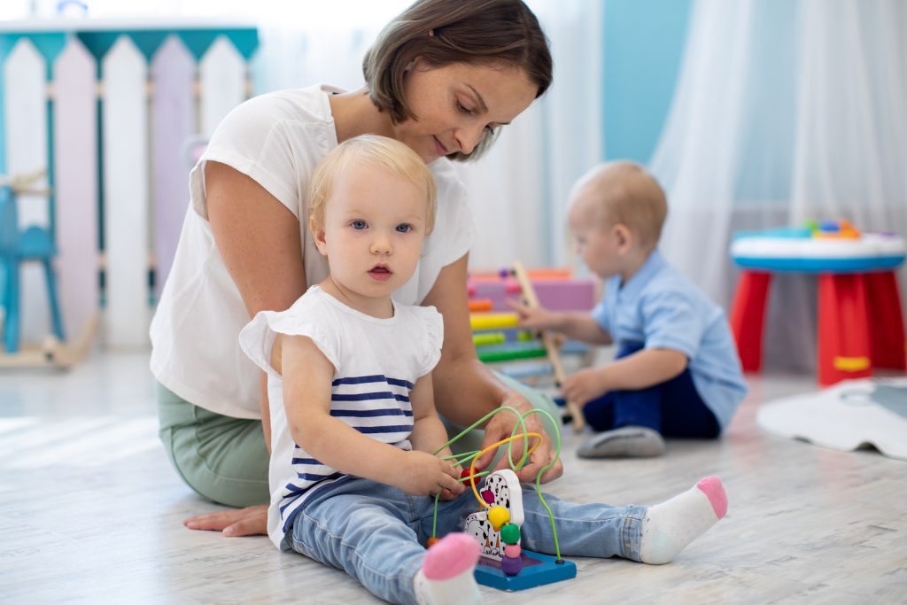 Woman with two kids on the floor, playing with toys | Unexpected benefits of hiring sleep training consultant | The Peaceful Sleeper