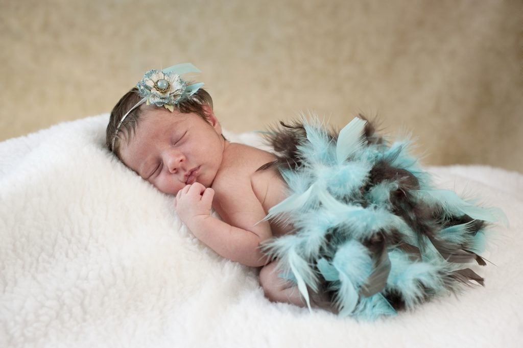 Newborn sleeping with boa of feathers. Peace of mind is one of the unexpected benefits of hiring a professional sleep consultant | The Peaceful Sleeper