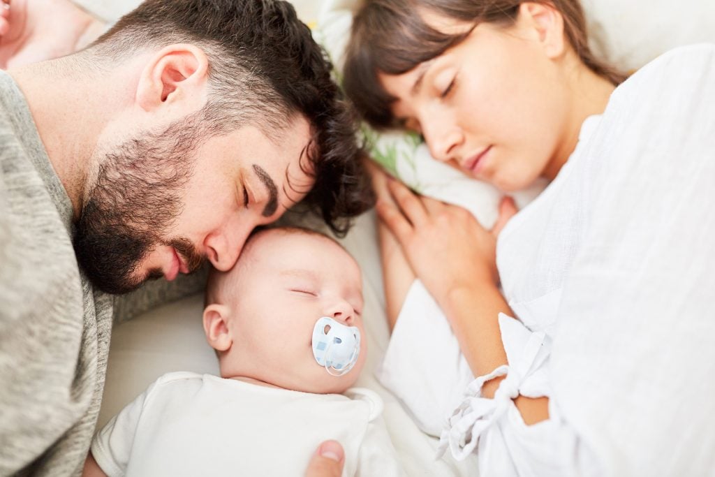 Sleeping parents and their little baby cuddle together relaxed benefit from expert sleep training professional and using a modified cry it out approach to sleep training | Sleep Training Consultant | The Peaceful Sleeper