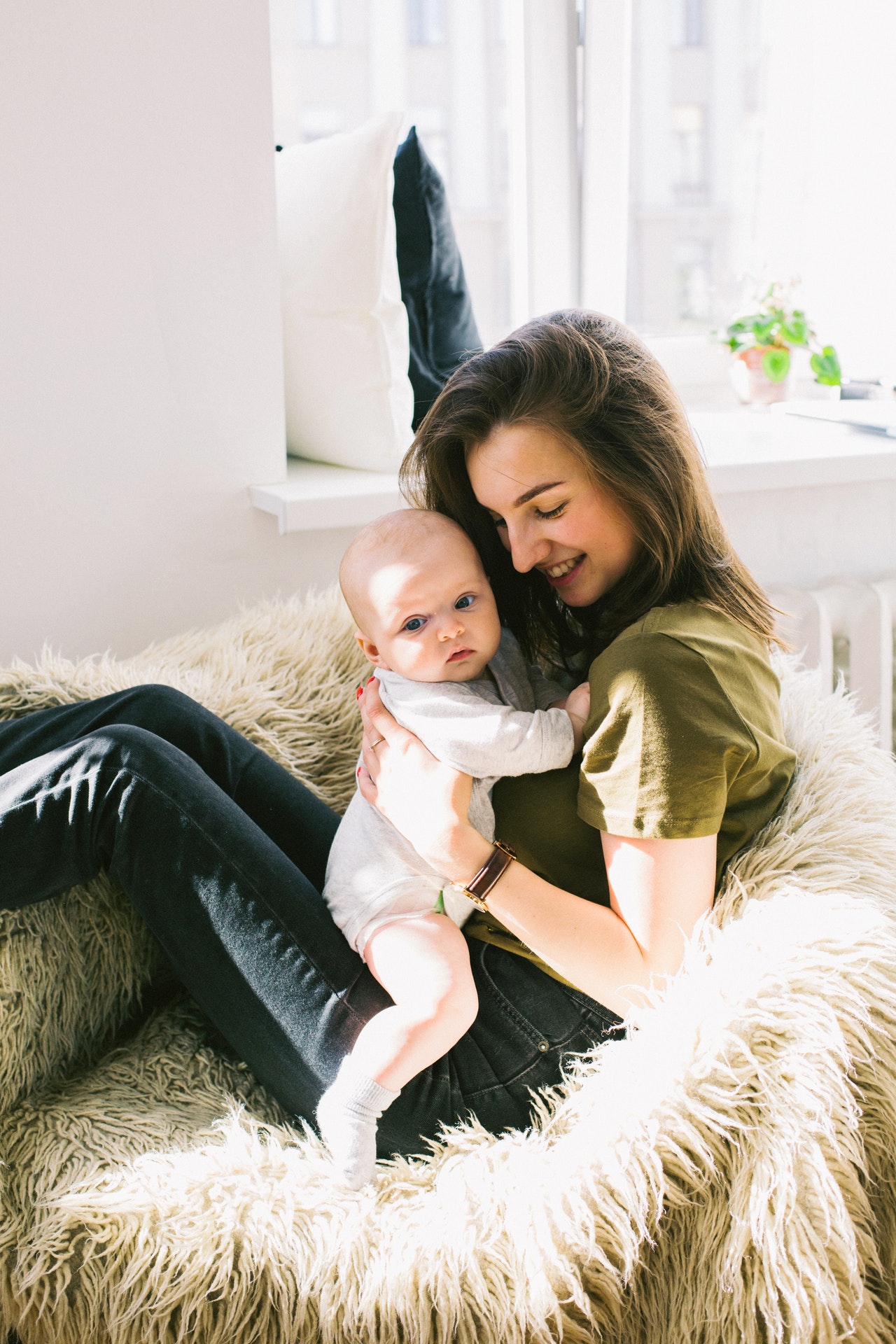 new mom in green shirt holding a newborn baby who won't sleep. Infant sleep consultant in Las Vegas, Chrissy Lawler, can help you learn how to get your newborn to sleep.