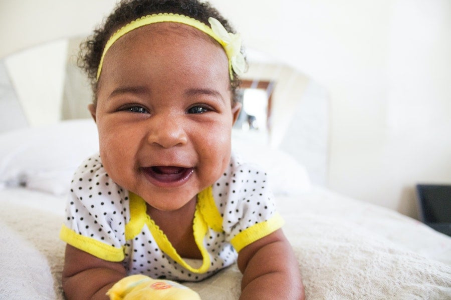 baby laying on a bed with a yellow bow | The Peaceful Sleeper 