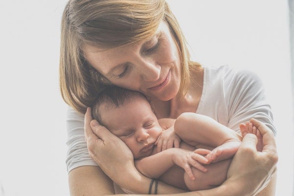 a woman holding a gassy baby to help relieve the pain | The Peaceful Sleeper 