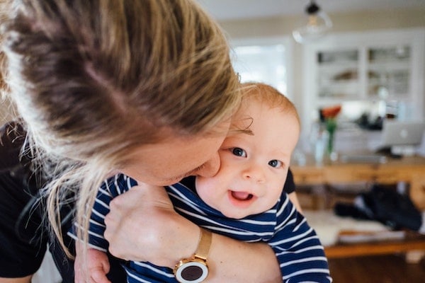 mother kissing her baby after taking him out of a swaddle | The Peaceful Sleeper 