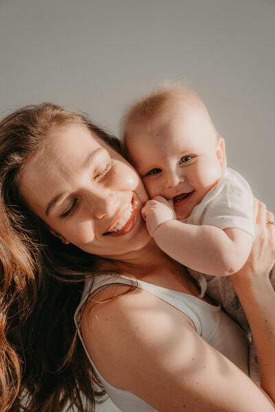 Mom Smiling Holding Baby - Sleep And Postpartum Well-Being | The Peaceful Sleeper