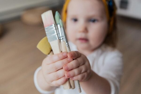 Baby Holding Paint Brushes | The Peaceful Sleeper